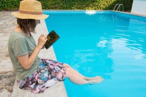 focused-woman-straw-hat-sitting-poolside